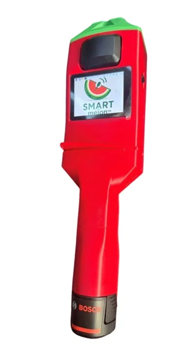 The handheld SMART tap device: a red cordless tool with a colour screen showing the SMART melon logo and a rechargeable battery in the handle.